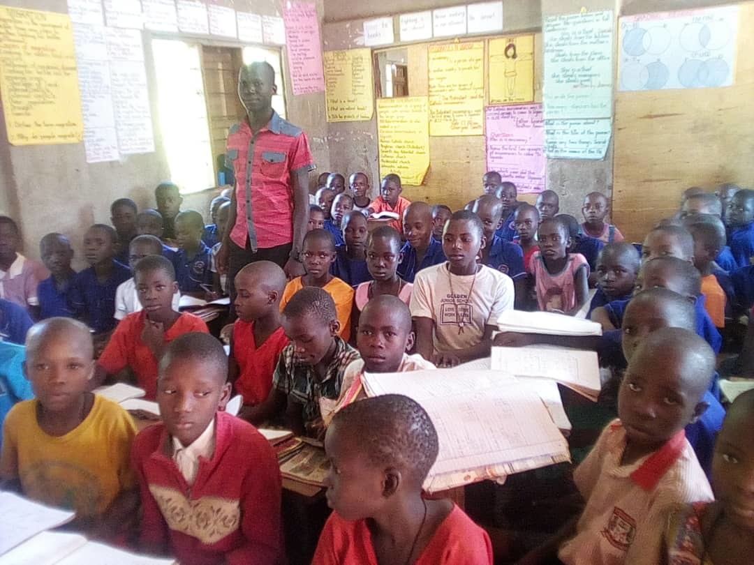 Eine Schulklasse in Afrika mit vielen Schülern. Die Schüler haben Hefte vor sich liegen.